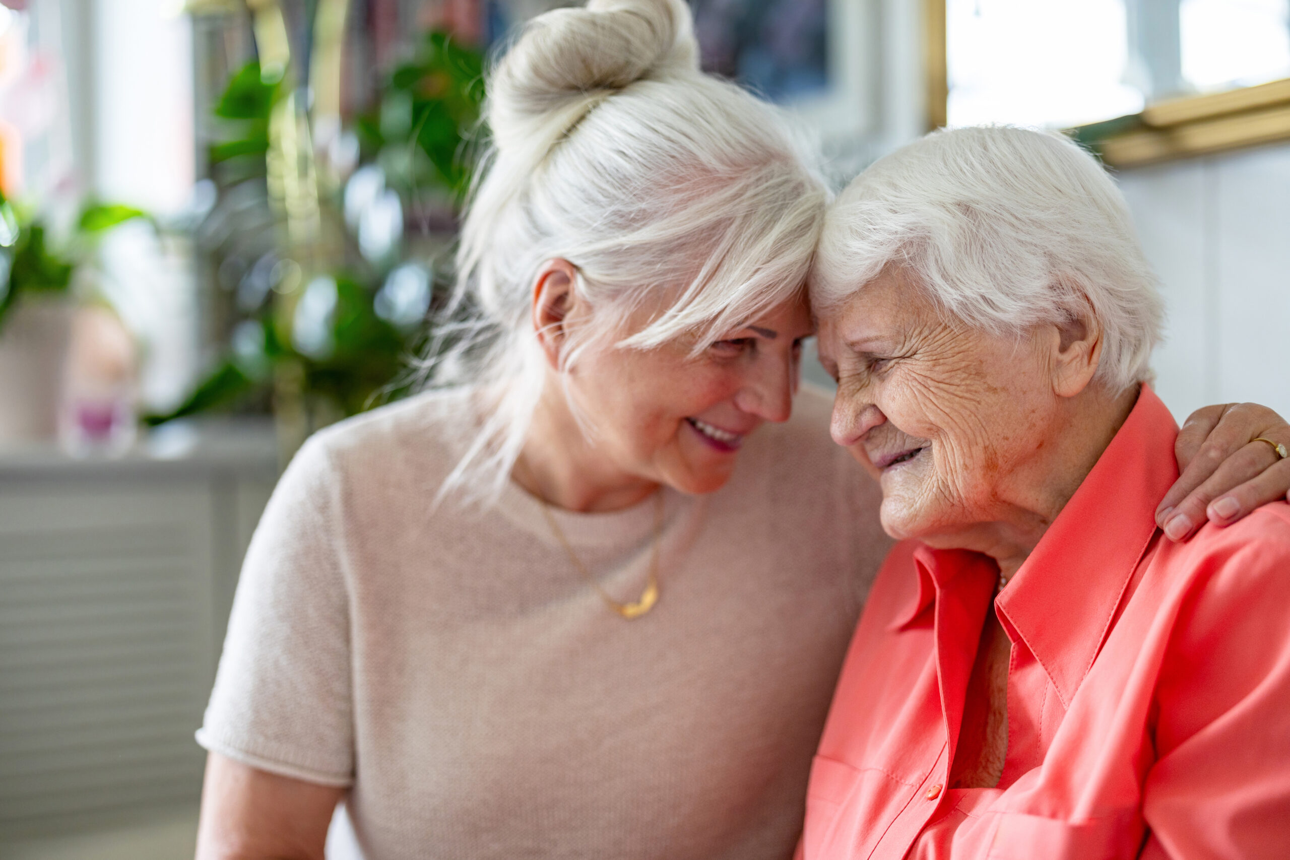 Smiling elderly woman with her adult caregiver at home